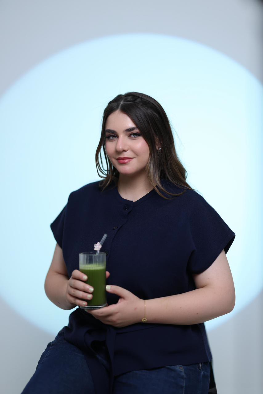 Mira, founder of Miraka, holding a glass of iced matcha
